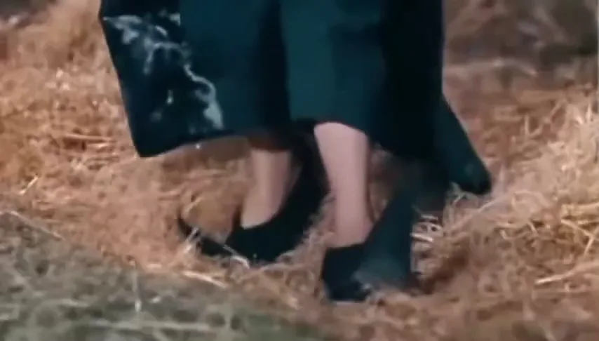 Close-up of the lead's feet in black heels tiptoeing across straw on the barn floor